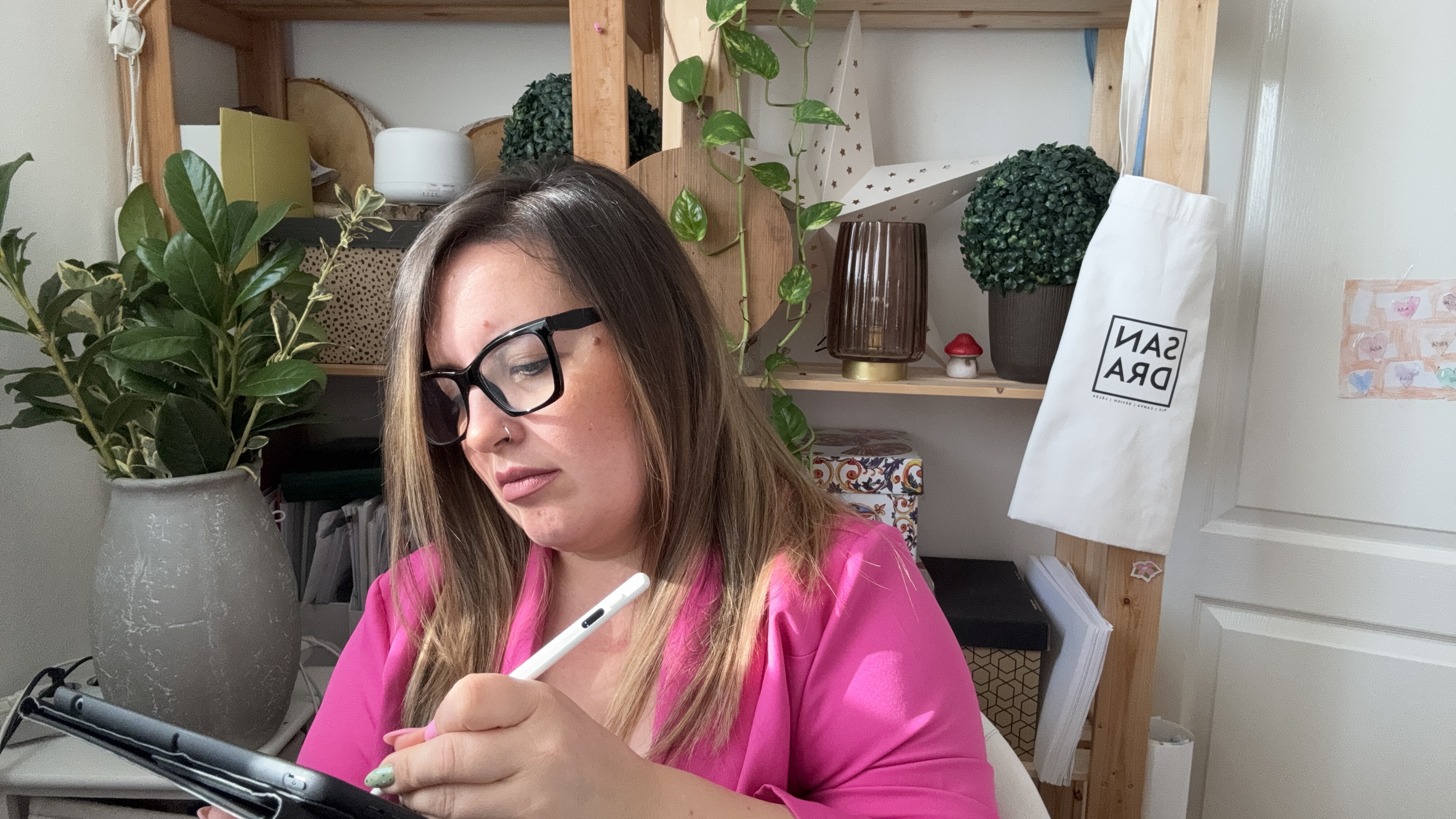 Alexandra a tabletjén dolgozik a növényekkel teli munkasarkában